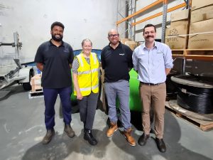 Four people stand in front of green NBN cable in a warehouse