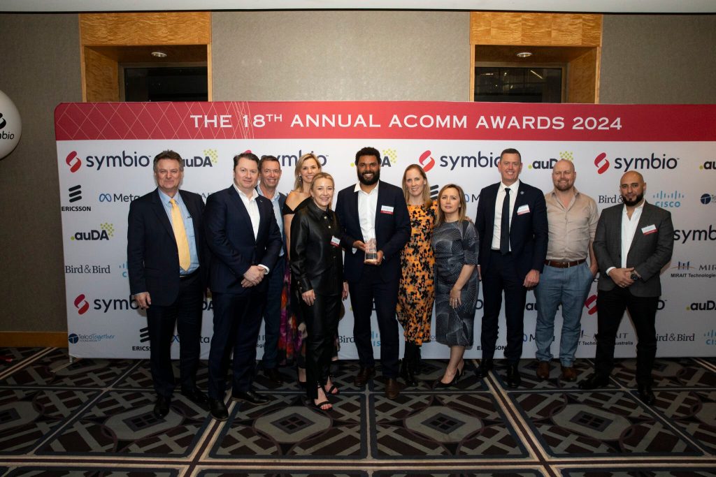 Group of people stand in front of banner for ACOMM Awards